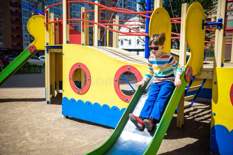 Sommer, Kindheit, Freizeit, Freundschaft und Leutekonzept - gl?cklicher kleiner Junge auf Kinderspielplatz schob vom H?gel lizenzfreies stockbild Sommer, Kindheit, Freizeit, Freundschaft und Leutekonzept - gl?cklicher kleiner Junge auf Kinderspielplatz schob vom H?gel lizenzfreies stockbild