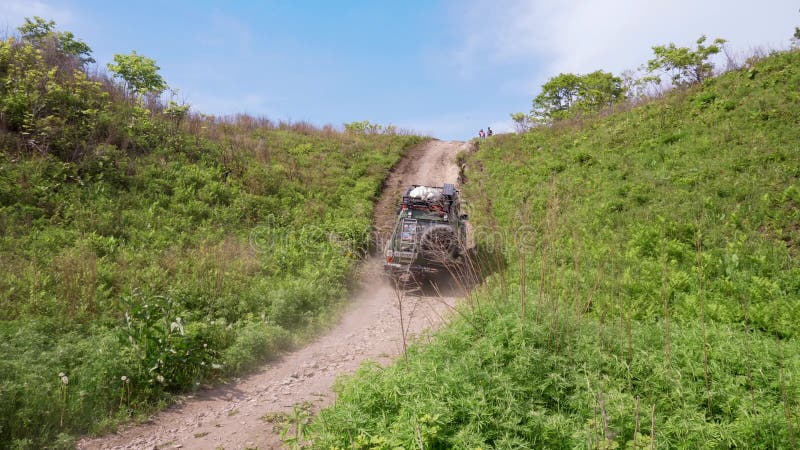 Sommer 2019 - Primorsky Krai, Russland - Ein grünes Expeditionsauto Nissan Safari fährt in einen steilen Hügel