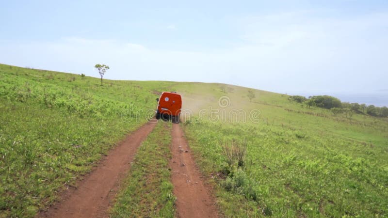 Sommer 2019 - Primorsky Krai, Russland - Orange Expedition Minibus Sable auf einer staubigen Straße zwischen Grünflächen