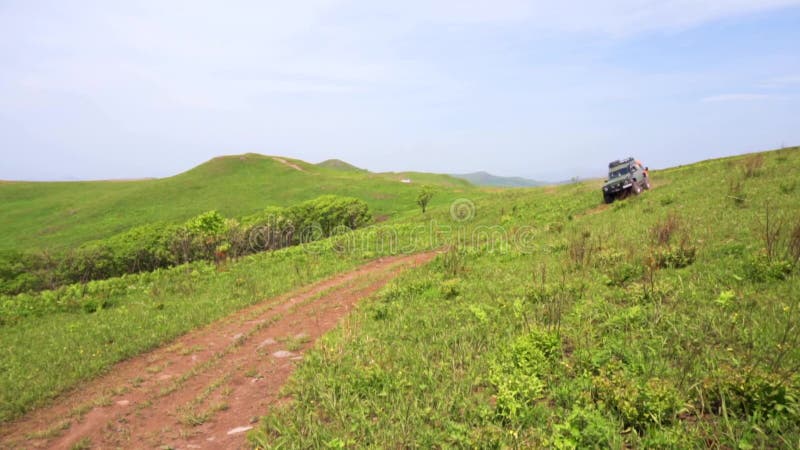 Sommer 2019 - Primorsky Krai, Russland - Orange Expedition Minibus Sable auf einer staubigen Straße zwischen Grünflächen