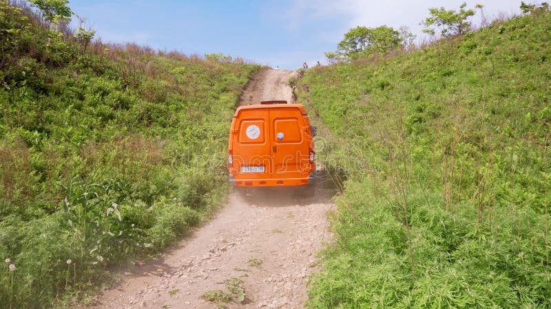 Sommer 2019 - Primorsky Krai, Russland - Orange Expeditionswagen Sable fährt auf einem steilen Hügel