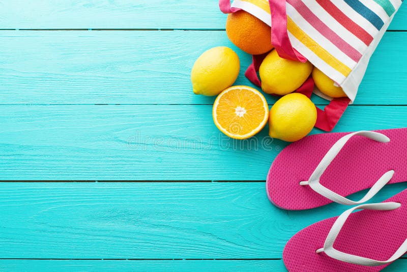 Summer fun time and fruits on blue wooden background. Mock up and picturesque. Orange, lemon fruit in bag and flip flops on the floor. Top view and copy space. Summer fun time and fruits on blue wooden background. Mock up and picturesque. Orange, lemon fruit in bag and flip flops on the floor. Top view and copy space