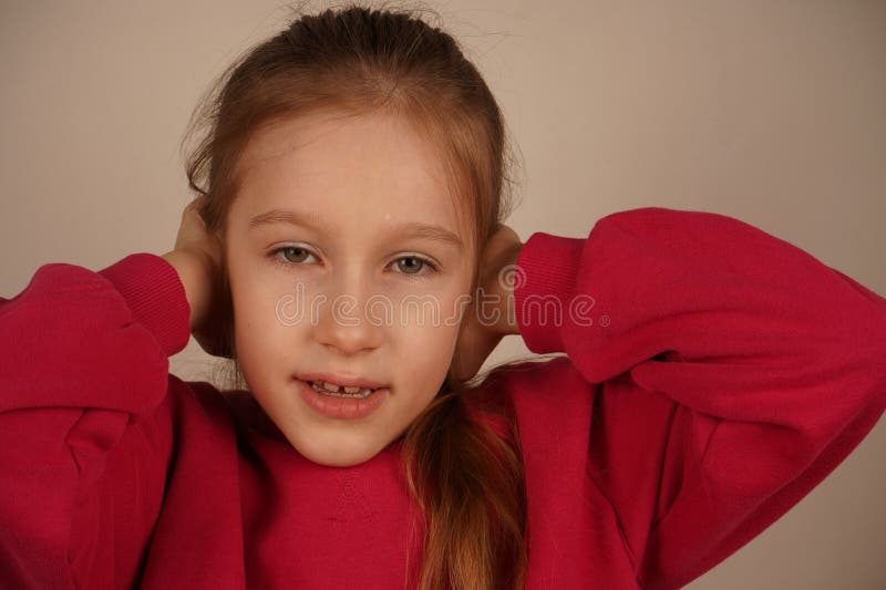 Son expression faciale reflète l'inconfort. Une représentation frappante de la surcharge sensorielle. Une rousse dans un capot rou photographie stock