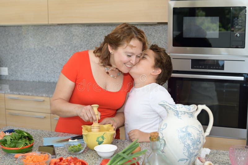 Son kisses his mother while they prepare lunch stock photo Son kisses his mother while they prepare lunch stock photo