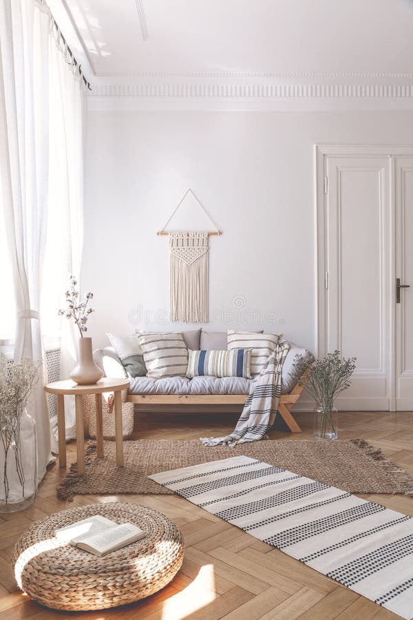 Sonnenstrahlen auf einem Weidenosmane- und Fischgrätenmusterboden eines beige Wohnzimmerinnenraums mit einem hölzernen Sofa und K stockfotografie Sonnenstrahlen auf einem Weidenosmane- und Fischgrätenmusterboden eines beige Wohnzimmerinnenraums mit einem hölzernen Sofa und K stockfotografie
