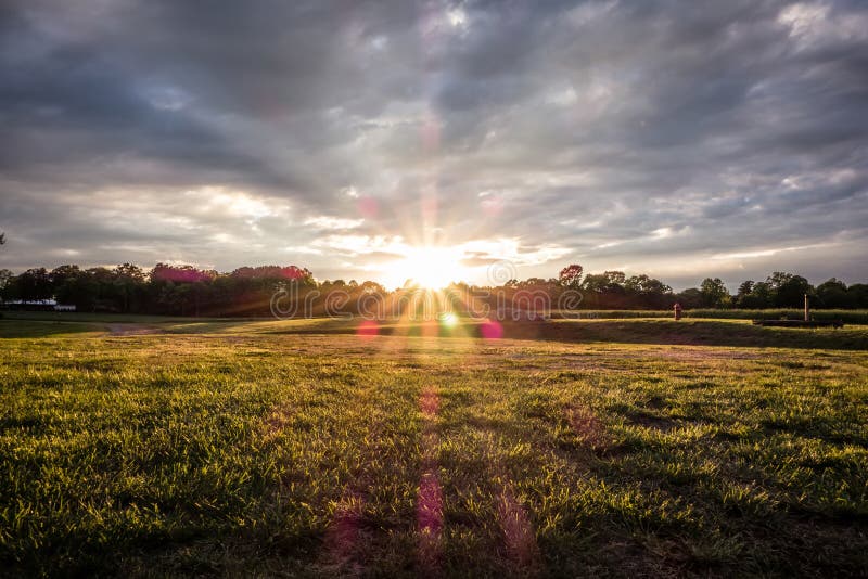Sonnenuntergang über grünem Bauernhof stockbild
