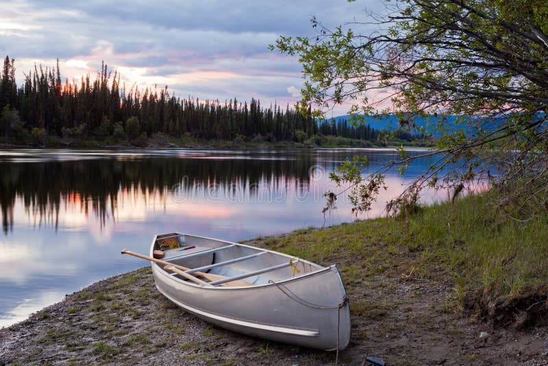 Sonnenunterganghimmel und -kanu in Teslin Fluss Yukon Kanada