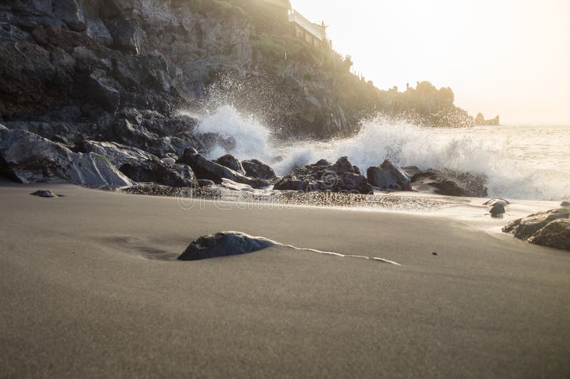 Sonnenunterganglicht über der Welle, die auf felsigem vulkanischem Strand spritzt stockfotos Sonnenunterganglicht über der Welle, die auf felsigem vulkanischem Strand spritzt stockfotos