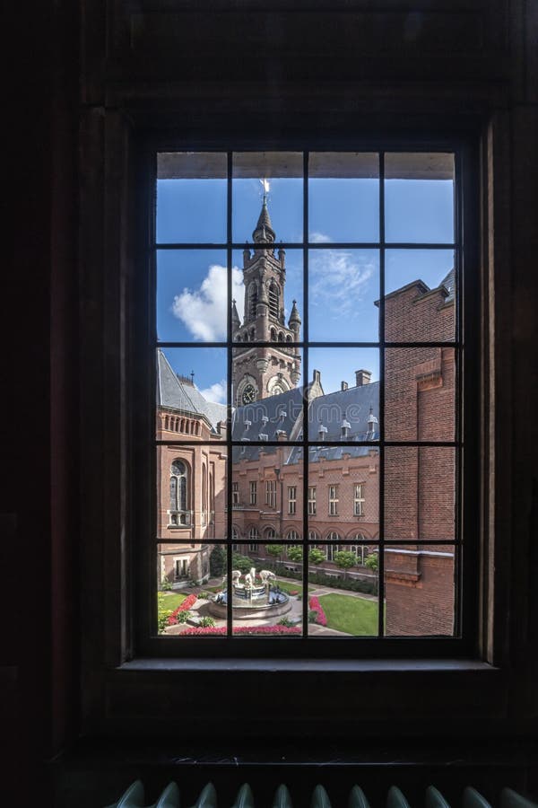 Window view of the distorted Peace Palace clock tower with the vintage and imperfect transparent glasses on the antique windows by a sunny and bright day, The Hague, Netherlands. Window view of the distorted Peace Palace clock tower with the vintage and imperfect transparent glasses on the antique windows by a sunny and bright day, The Hague, Netherlands