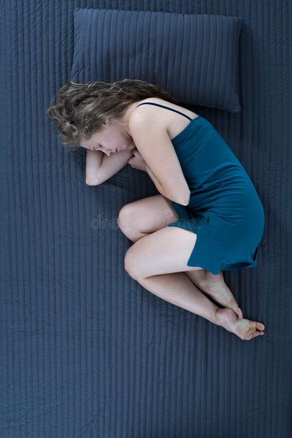 женщина сидит в позе эмбриона на диване