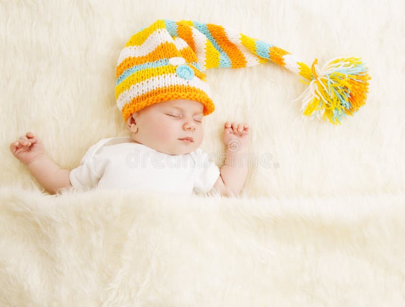 Sono do bebê no chapéu, criança recém-nascida de sono na cama, recém-nascido adormecido fotografia de stock Sono do bebê no chapéu, criança recém-nascida de sono na cama, recém-nascido adormecido fotografia de stock