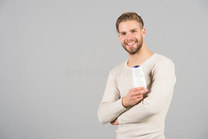 Sonrisa del soltero con la botella del champú o del gel a disposición, higiene foto de archivo libre de regalías Sonrisa del soltero con la botella del champú o del gel a disposición, higiene foto de archivo libre de regalías