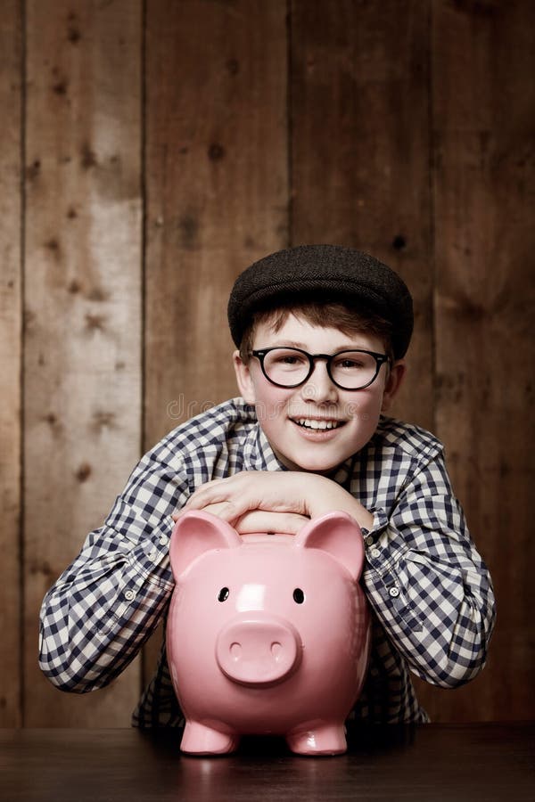 Sonrisa en el banco y retrato de un niño pequeño con crecimiento del ahorro o éxito de la inversión en su hogar. aprendizaje de fi foto de archivo