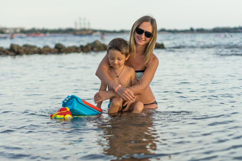 Sonrisa y madre feliz y su hijo que juegan y que corren en la playa Concepto de familia amistosa imagen de archivo libre de regalías Sonrisa y madre feliz y su hijo que juegan y que corren en la playa Concepto de familia amistosa imagen de archivo libre de regalías