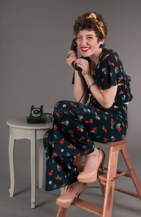 Sonrisas bobas modelas de la muchacha mientras que en el teléfono pasado de moda fotografía de archivo Sonrisas bobas modelas de la muchacha mientras que en el teléfono pasado de moda fotografía de archivo