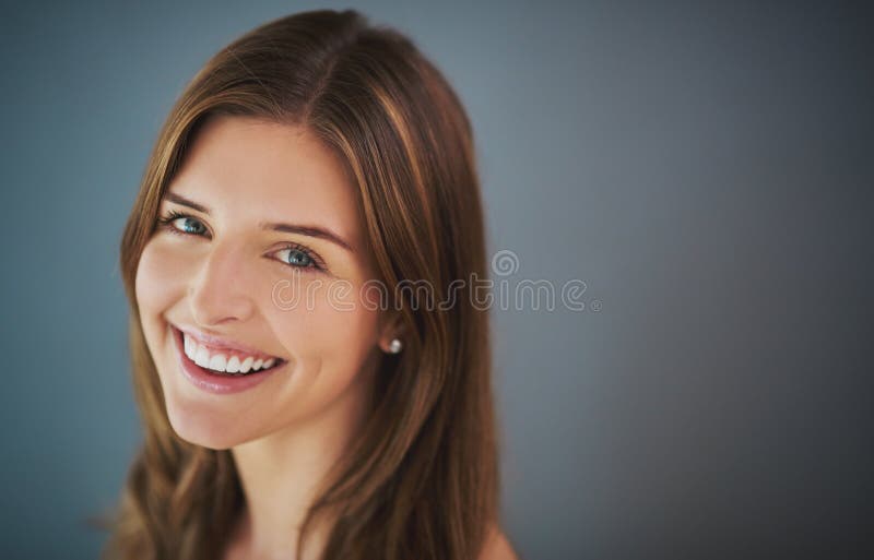 Smiles of certainty. Studio portrait of an attractive young woman posing against a gray background. Smiles of certainty. Studio portrait of an attractive young woman posing against a gray background