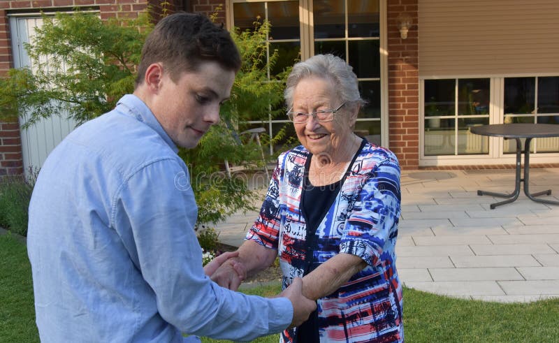 Sonsonen hjälper hans stor-mormor att gå royaltyfria bilder Sonsonen hjälper hans stor-mormor att gå royaltyfria bilder