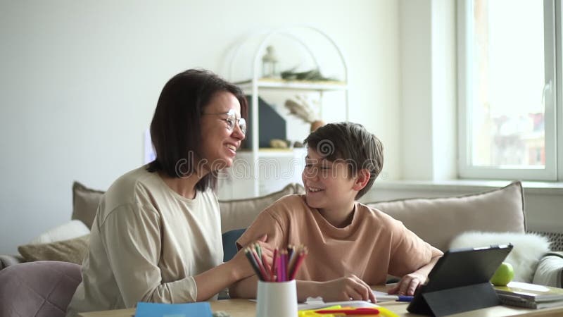 Sonstudent och mamma gör läxor tillsammans med spbd. skoluppgift i den lyckliga familjen med Tablet gadget. arkivfilmer