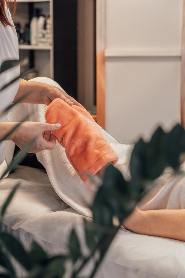 A spa professional gently wraps a clients hand in a warm, soft towel, highlighting relaxation and skin care. The serene setting emphasizes the nurturing touch and pampering experience. Pampering experience stock images, royalty-free photos and pictures