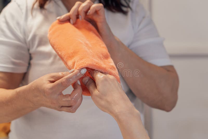 A spa professional gently wraps a clients hand in a warm, soft towel, highlighting relaxation and skin care. The serene setting emphasizes the nurturing touch and pampering experience. Pampering experience stock images, royalty-free photos and pictures