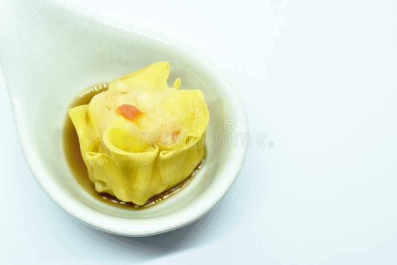 Sopa china rellena de camarón y cerdo con salsa de soja en cuchara de fondo blanco