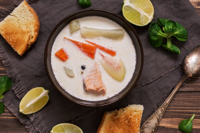 A sopa cremosa dos salmões com batatas e cenouras serviu com brinde em uma tabela rústica de madeira da prancha Kalakeitto finlan foto de stock royalty free A sopa cremosa dos salmões com batatas e cenouras serviu com brinde em uma tabela rústica de madeira da prancha Kalakeitto finlan foto de stock royalty free