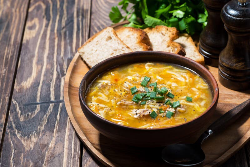 Sopa de galinha com macarrão de ovo sobre fundo de madeira imagens de stock
