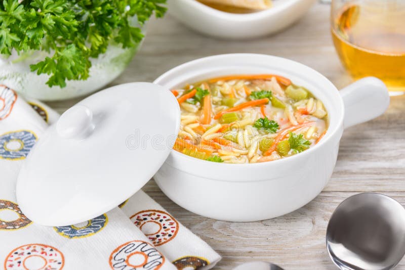 Sopa del orzo del pollo en un cántaro blanco en fondo de madera Sopa italiana con las pastas del orzo fotos de archivo libres de regalías Sopa del orzo del pollo en un cántaro blanco en fondo de madera Sopa italiana con las pastas del orzo fotos de archivo libres de regalías