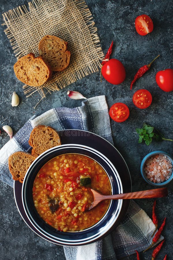 Sopa hecha en casa deliciosa de la lenteja roja, de verduras, de la albahaca, del ajo y del pedazo orgánicos de pan negro en la t foto de archivo libre de regalías Sopa hecha en casa deliciosa de la lenteja roja, de verduras, de la albahaca, del ajo y del pedazo orgánicos de pan negro en la t foto de archivo libre de regalías