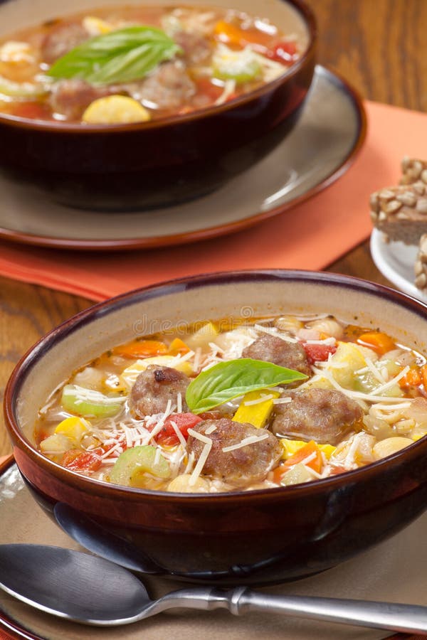 Two bowls of hot fresh Italian Meatball Soup and wholegrain bread. Two bowls of hot fresh Italian Meatball Soup and wholegrain bread