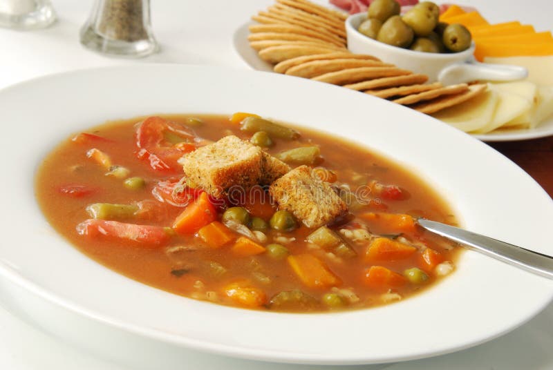 Steaming hot vegetable soup with crackers and cheese for appetizers. Steaming hot vegetable soup with crackers and cheese for appetizers