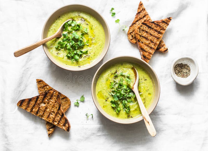 A sopa vegetal triturada da mola serviu com micro verdes e os biscoitos inteiros da grão em um fundo claro Vegetariano saudável foto de stock A sopa vegetal triturada da mola serviu com micro verdes e os biscoitos inteiros da grão em um fundo claro Vegetariano saudável foto de stock