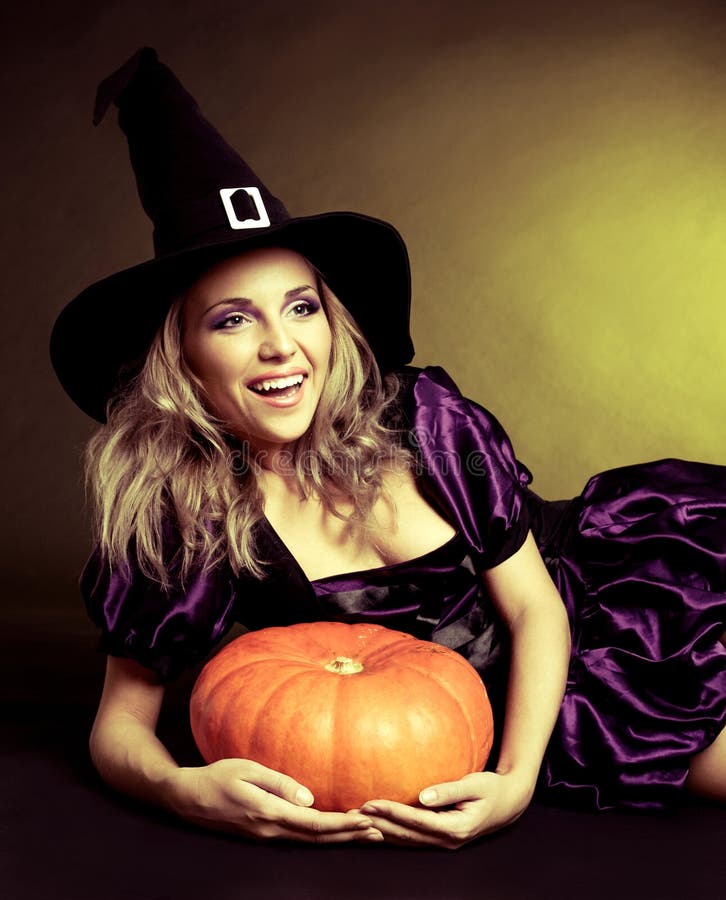 Happy young witch with a pumpkin, against yellow studio background. Happy young witch with a pumpkin, against yellow studio background