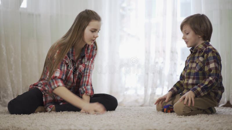 Sorella pi? anziana e fratello minore del ritratto che giocano insieme seduta sul pavimento sul tappeto lanuginoso Il gioco del r