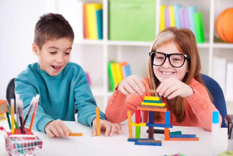 Sorella più anziana sorridente che gioca con il fratello piccolo con il blo di legno fotografie stock