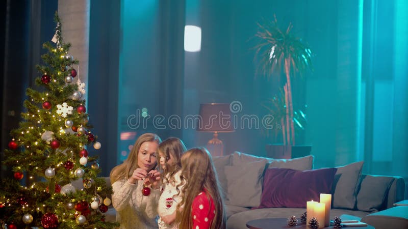 Sorelle decorano l'albero di Natale con la madre a casa archivi video