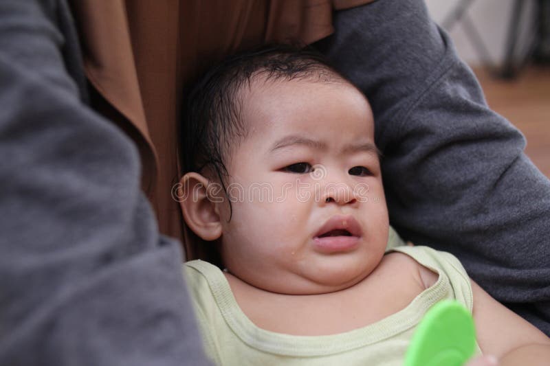 Sorellina musulmana asiatica si prende cura del fratello confortante e si nutre del figlio immagine stock