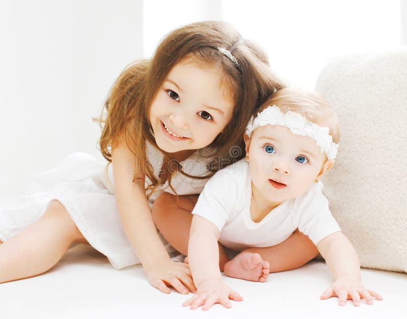 Sorelline insieme, bambini che giocano nella stanza bianca immagine stock Sorelline insieme, bambini che giocano nella stanza bianca immagine stock