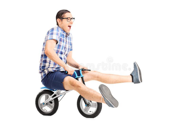 Sorgloser junger Kerl, der ein kleines Fahrrad reitet