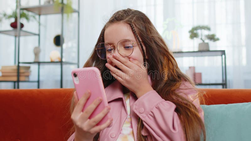 Sorprendida muchacha con el pelo barrido por el viento usando un smartphone sonriendo recibe un mensaje de buena noticia por corre