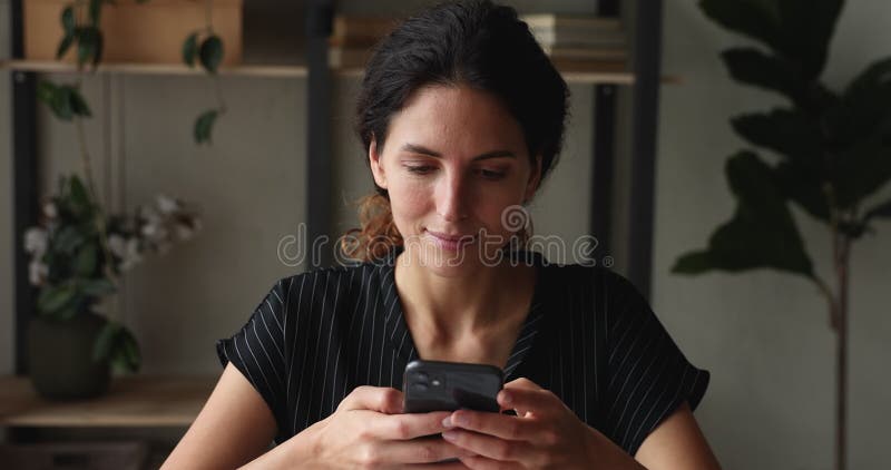 Sorridente e atraente mensagem de mensagem de mensagem de mulher milenar no smartphone.