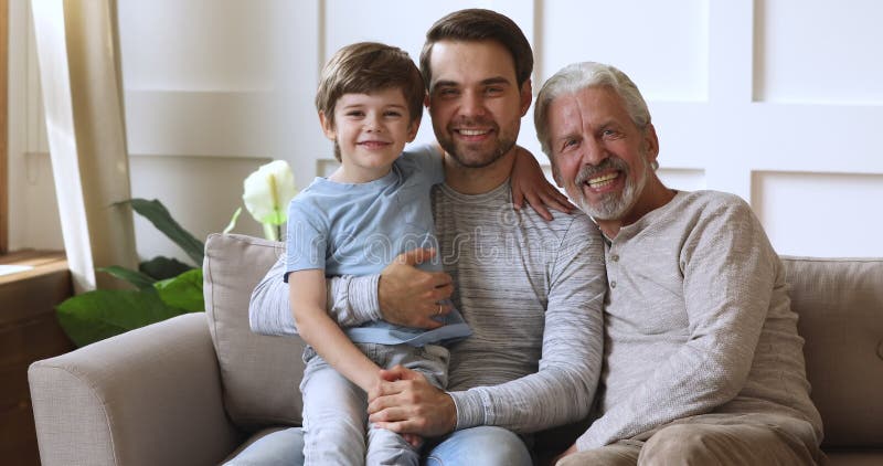 Sorridente família de três gerações masculinas descansando no sofá.