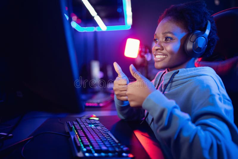 Sorridete ritratto di una giovane donna africana giocatore professionista che gioca online con un computer neon color immagine stock libera da diritti