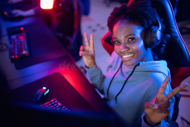 Sorridete ritratto di una giovane donna africana giocatore professionista che gioca online con un computer neon color fotografia stock libera da diritti