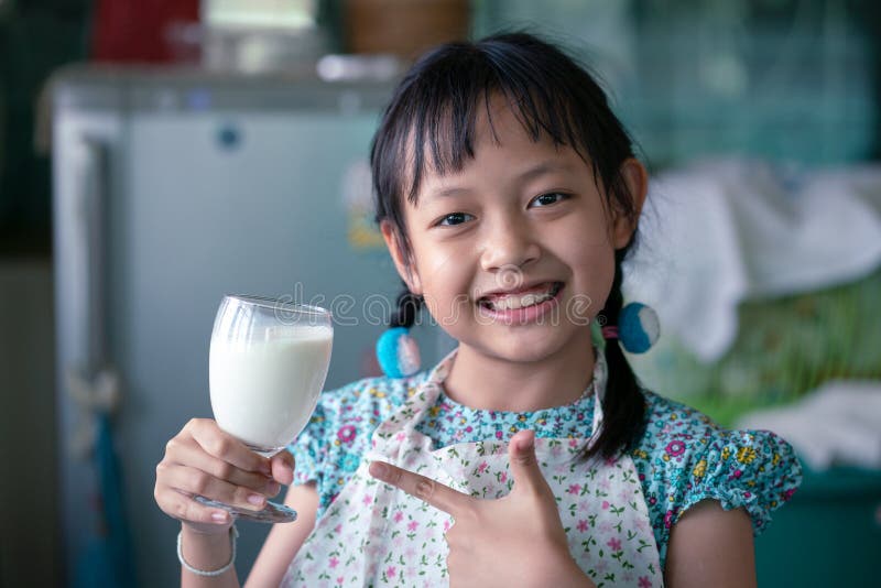 Sorridi bambina asiatica che regge un bicchiere di latte fotografia stock libera da diritti