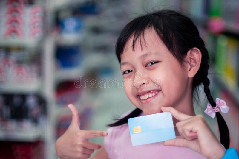 Sorridi bambina con la carta di credito al supermercato fotografia stock