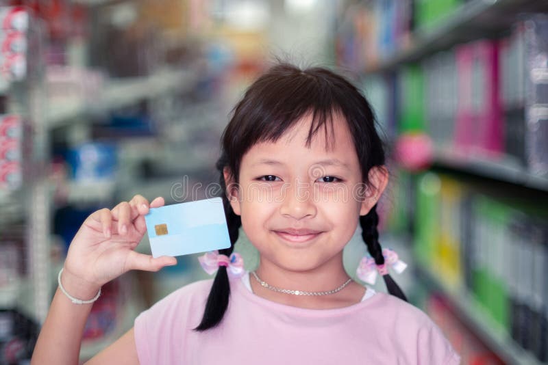 Sorridi bambina con la carta di credito al supermercato immagine stock