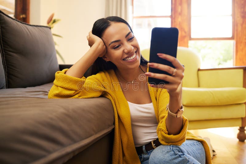 Jovem mulher sorrindo e rindo enquanto envia mensagens de texto em um  telefone em casa mulher alegre conversando com seus amigos com aplicativos  rolando mídias sociais e assistindo memes engraçados da internet enquanto  relaxa em um sofá