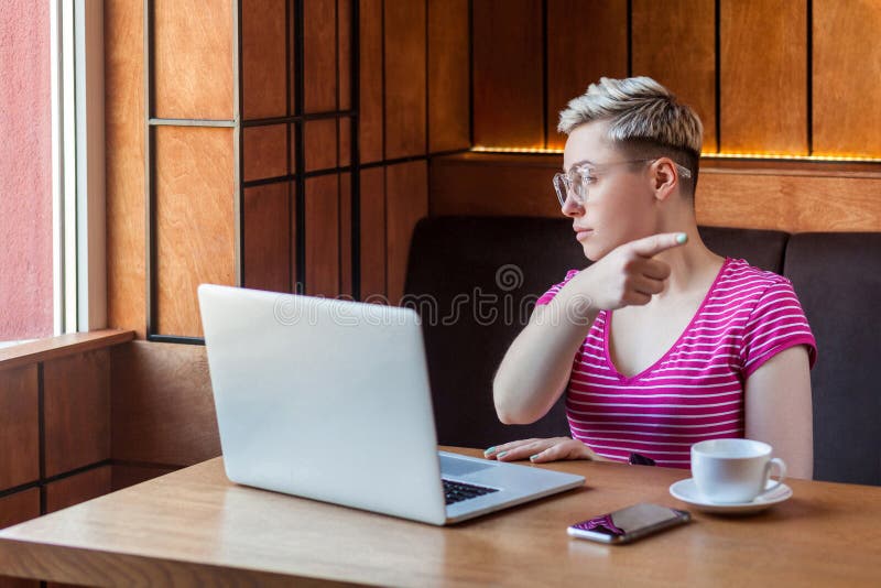 Sors d'ici Portrait d'une jeune femme adulte triste et sérieuse aux cheveux courts en t-shirt rose et lunettes est assise dans un photo libre de droits