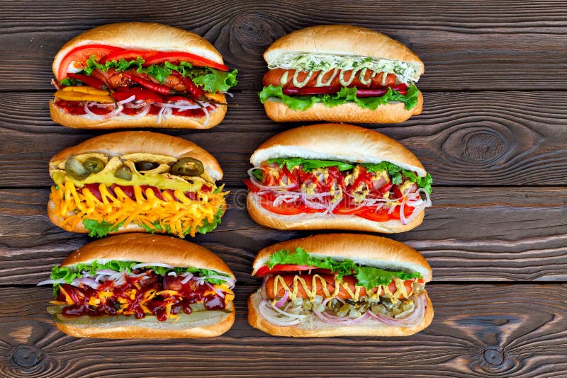 Sort de grands hot-dogs délicieux avec de la sauce et des légumes sur le fond en bois photos libres de droits Sort de grands hot-dogs délicieux avec de la sauce et des légumes sur le fond en bois photos libres de droits